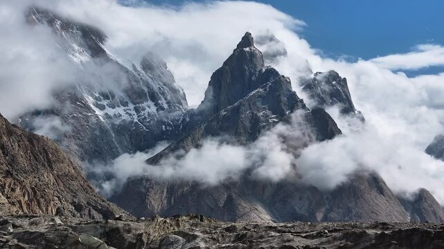 The Karakoram Mountains in Pakistan shrouded in low-hanging clouds on a sunny day. Captured on the way to K2 Base Camp.