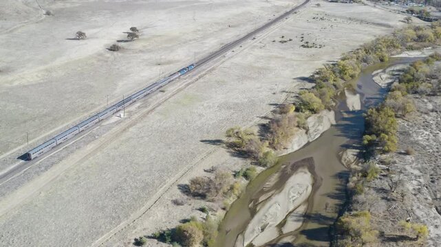4K aerial pan of Amtrak's Coast Starlight as it moves through the yellow pastures of Bradley California along the Salinas River.