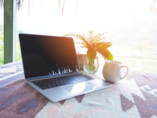 White cup of coffee and blank screen laptop computer on holiday vacation.