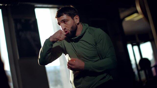 Professional boxer shadow boxing, throwing precise punches, honing skills in dark gym, highlighting intense training and athletic commitment