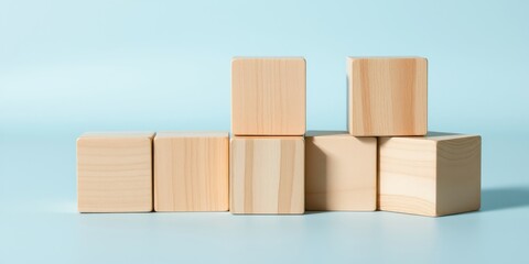 Obraz premium A simple arrangement of wooden blocks against a light blue background. The blocks are unpainted and natural, with a subtle grain pattern.