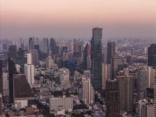 Fototapeta premium Bangkok high aerial view from the Chao Phraya River to Bang Rak and Si Lom districts at sunset. A large asian capital city with skyscrapers and millions of inhabitants. High quality panoramic photo