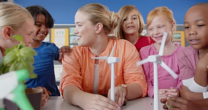 In school, female teacher and students learning about wind turbines in classroom