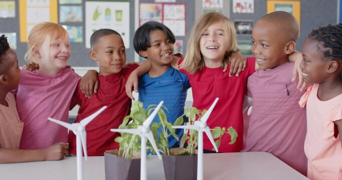 In school, diverse group of children smiling and hugging near wind turbines