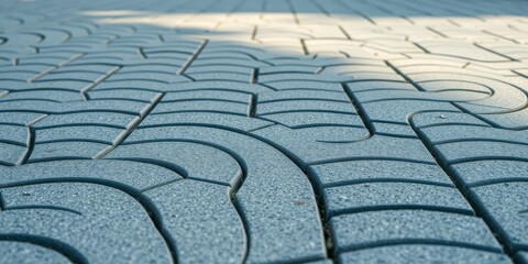 Close-up of a textured pavement surface featuring a repeating pattern of interlocking curved shapes, reminiscent of a labyrinth or an intricate design
