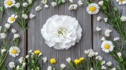 Obraz premium A white carnation surrounded by smaller wildflowers, placed on a wooden surface.