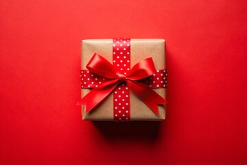 Top view photo of decorations gift boxes with red ribbon bow on dark red background.