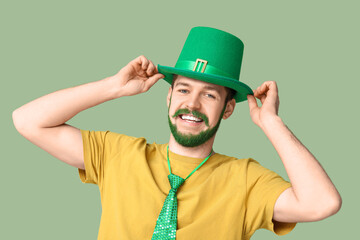 Young man in leprechaun hat with green beard on green background. St. Patrick's Day celebration