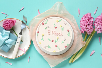 Sweet bento cake with gift box and beautiful flowers on turquoise background. International Women's Day