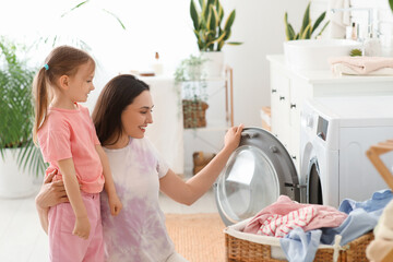 Mother teaching her daughter to do laundry at home