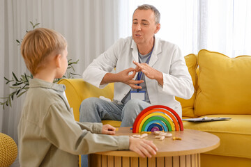 Male speech therapist working with little boy in office