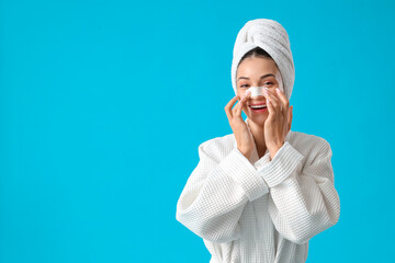 Young woman applying nose patch against blue background
