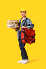 Asian female courier with pizza boxes on yellow background