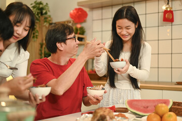 Warm asian family enjoying traditional dishes during Chinese New Year reunion dinner