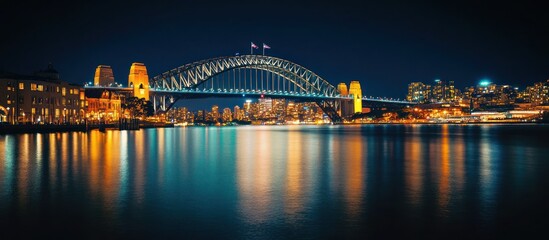 Fototapeta premium Night cityscape with illuminated bridge and city skyline reflected in water.