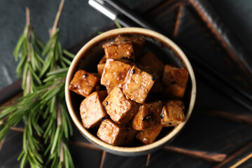 Bowl with pieces of fried tofu cheese and rosemary on dark background