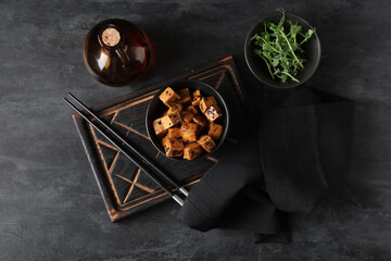 Bowl with pieces of fried tofu cheese and micro green on black background
