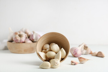 Wooden bowl with fresh garlic cloves on white background