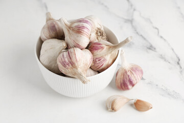 Bowl with fresh garlic and cloves on white background