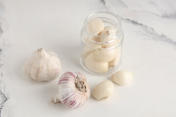 Jar with fresh garlic cloves on white background