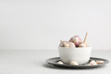 Bowl with fresh garlic on white background