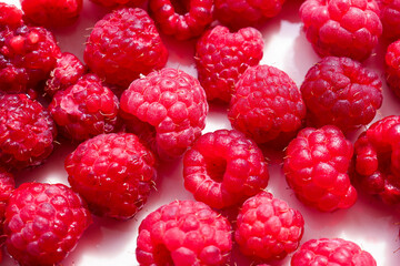 Fresh raspberries are scattered on a white background.