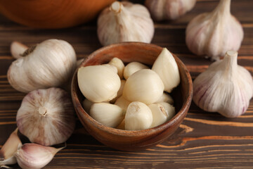Bowl with fresh garlic cloves on wooden background