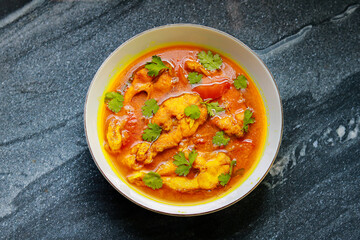 Fish curry in a bowl on a black table. Top view, flat lay