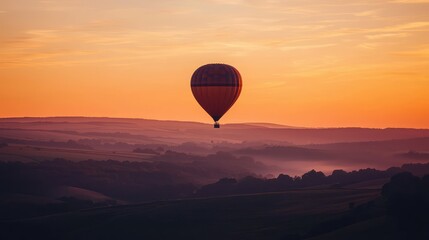 Obraz premium Colorful Hot Air Balloon Soaring in Vibrant Sunset Sky Over Hills