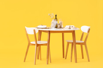 Served restaurant table with flowers on yellow background