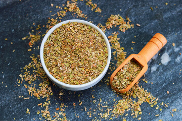 Dried Oregano in a bowl on a dark background. Top view.