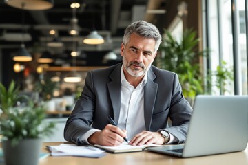 Fototapeta premium Business professional in a modern office setting, focused and writing notes, surrounded by plants and soft lighting.