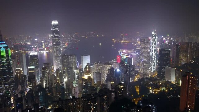 Aerial: The Vibrant Hong Kong Skyline And Harbor Sparkle At Night With Brightly Lit Skyscrapers, Ferries, And A Glowing Waterfront, Representing The City'S Dynamic Nightlife