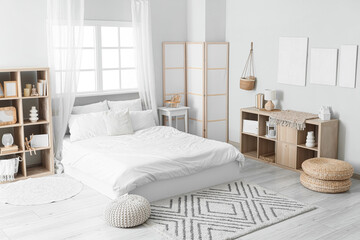 Interior of light bedroom with paintings, shelf units and folding screen