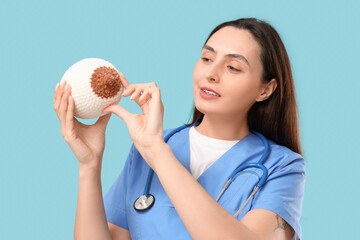 Female doctor with knitted breast model on blue background, closeup