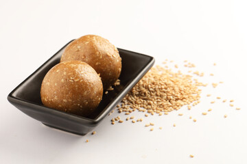 Tilgul Laddu or Til Gul balls for makar sankranti, it's a healthy food made using sesame, crushed peanuts and jaggery. served in a bowl. selective focus showing details.