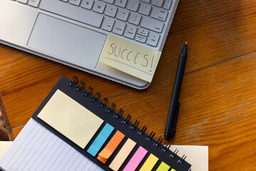 Organized workspace with a laptop, sticky notes, a notebook and a pen on a desk with the text 
