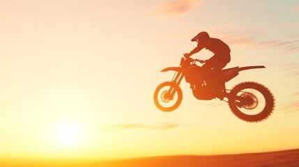 Silhouette of off-road motorcyclist jumping against sunset sky in desert