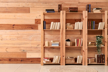 Bookshelves with plant near wooden wall in room