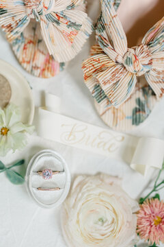 Floral bridal slippers, engagement ring, flowers, and "Bride" ribbon.