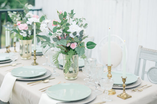Elegant tablescape with florals, pastel plates, and gold accents.