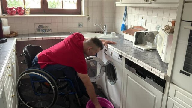 Strong man in a wheelchair fills the washing machine to wash laundry