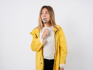 Very hungry Beautiful teen girl wearing rain coat holding spoon into mouth dream of tasty meal