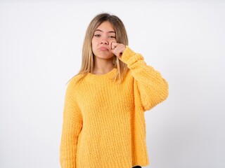 Displeased annoyed Beautiful caucasian teen girl wearing orange sweater clenches fists, gestures pissed, ready to revenge, looks with aggression at camera stands full of hate, being pressured
