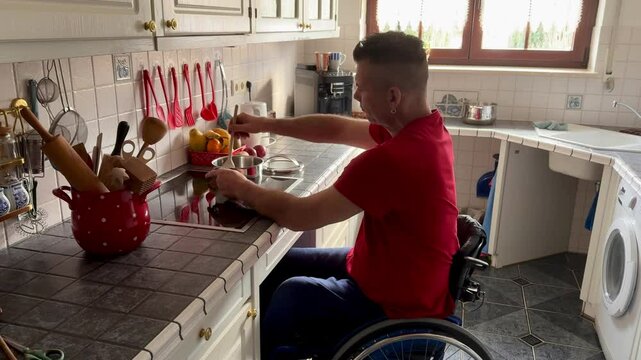 disabled man in wheelchair is in the kitchen and cooking in a pot on the stove