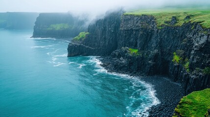 Foggy cliffs meet ocean waves, green coast, dramatic seascape.