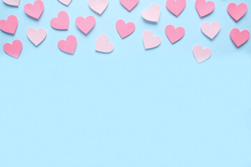 Blue background with pink heart shaped paper cutouts in minimalist design