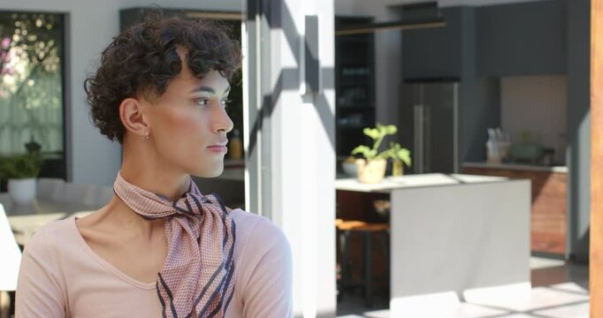 Smiling non binary person standing in modern kitchen, enjoying peaceful moment
