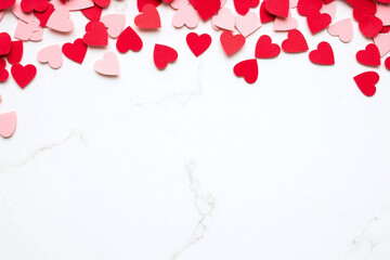 Festive romantic setup with red heart confetti on white surface