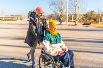 Young man pushing friend in wheelchair in park